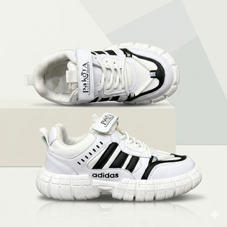 کتانی ورزشی نوجوان طرح adidas رنگ سفید با سه خط مشکی و بند چسبی Pakota روی سکوی استودیویی